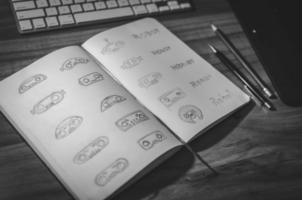 Pencil logo sketches filling a notebook spread